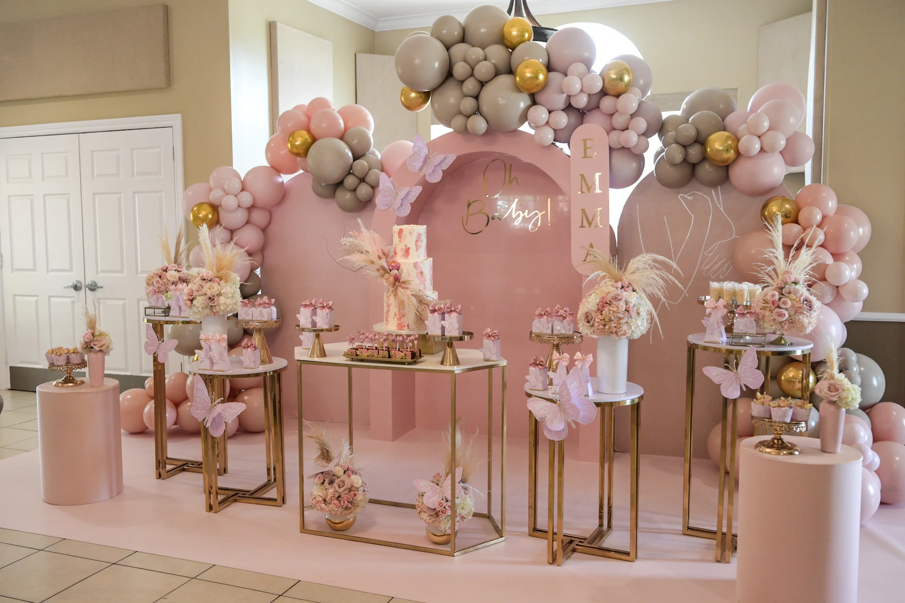 Coordinated pink, neutral and gold party backdrop showing a focused high-impact event design