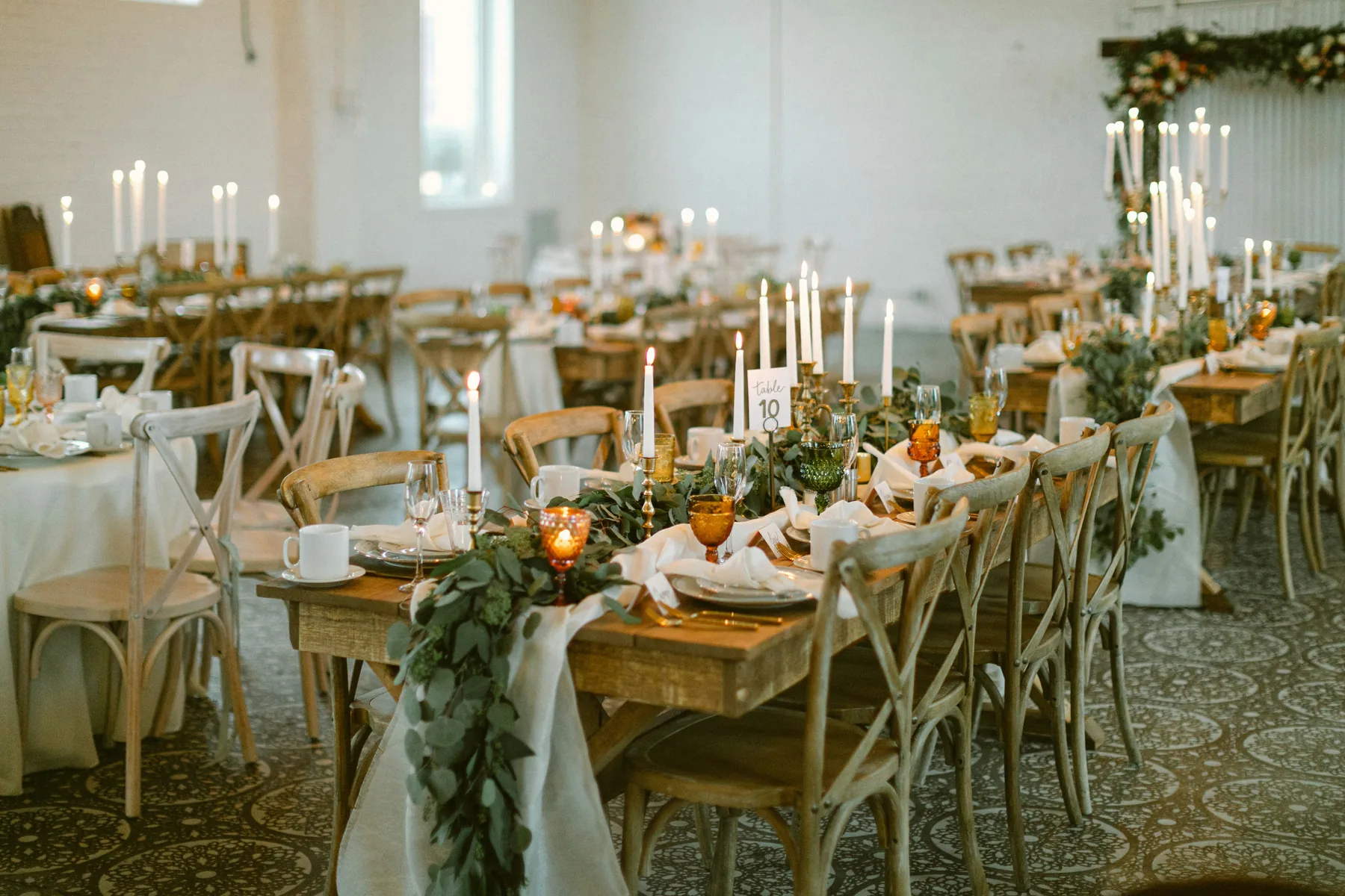 Reception tables with candles and greenery arranged as a cohesive event design